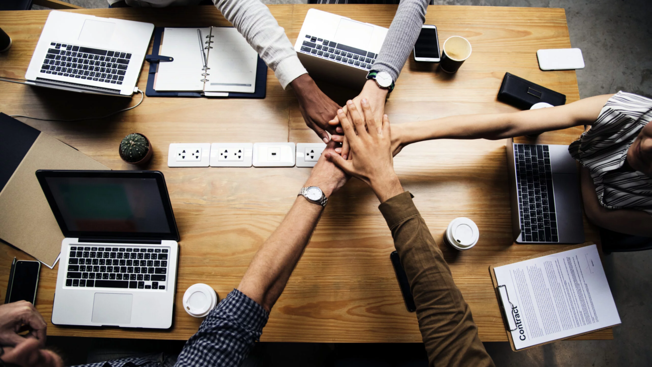 team-of-business-people-stacking-hands-scaled_EN